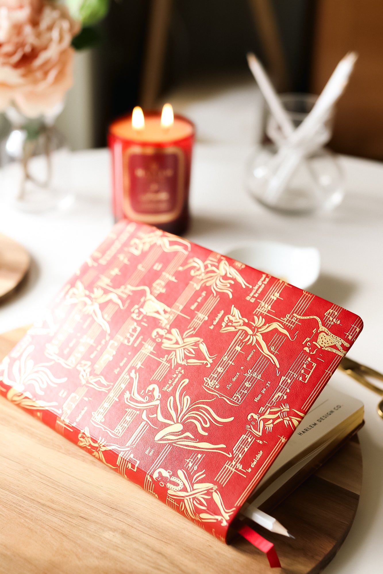 The red journal on a table with a pencil.