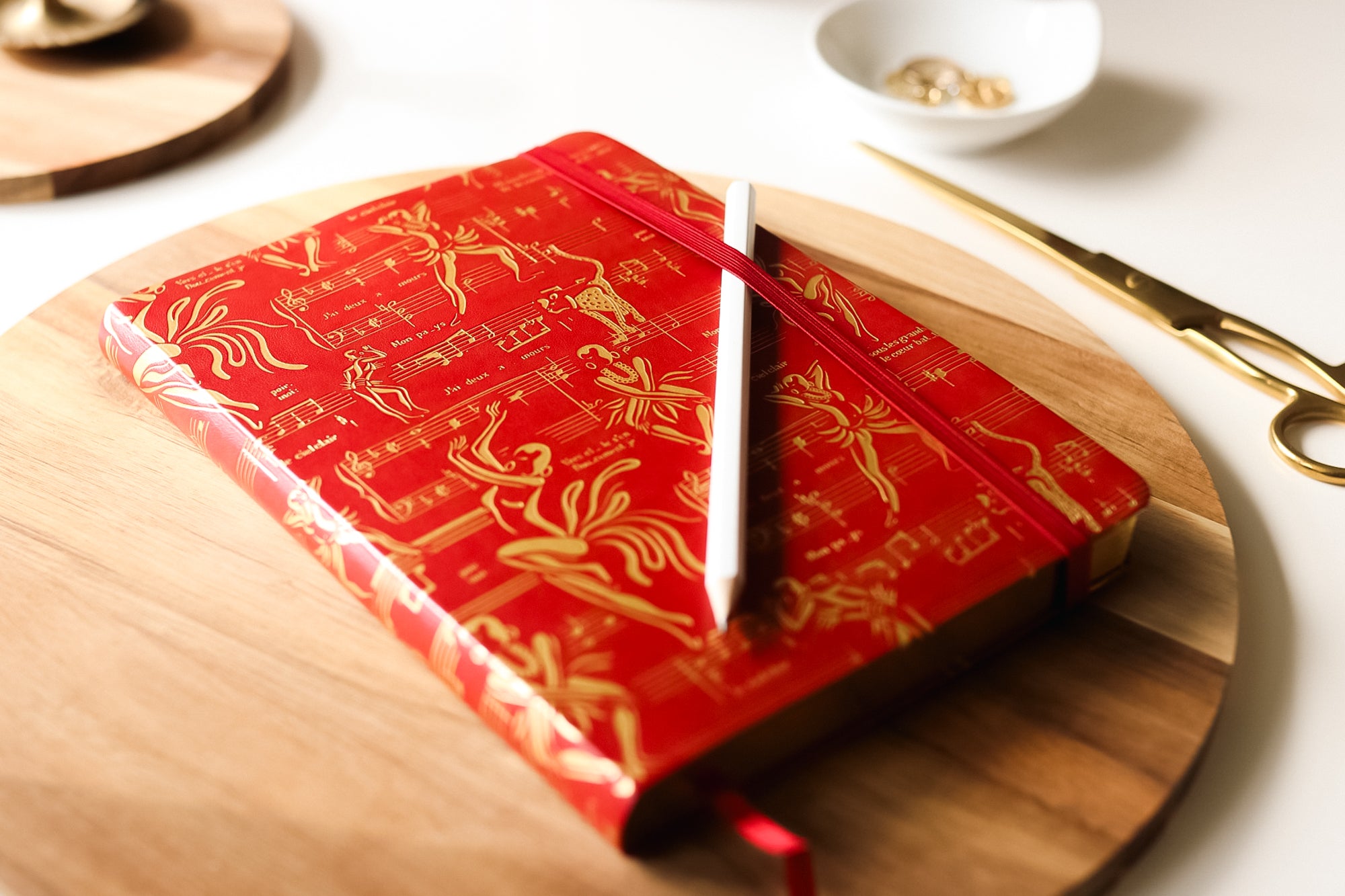 The red journal on a table with a pencil.