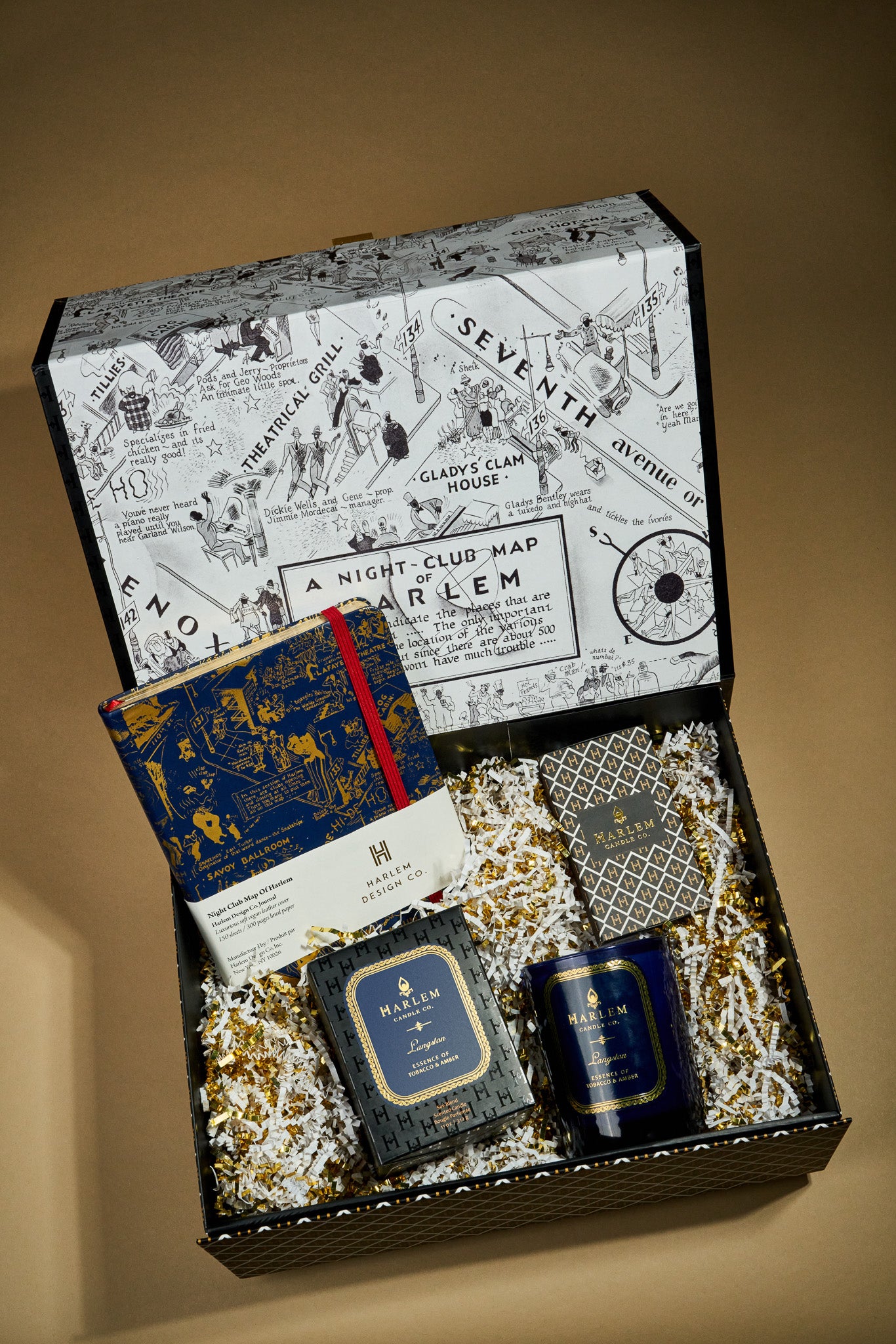 This is an image of our Langston Dreams gift box which includes the Langston candle, blueThis is an image of our Langston stories gift box which includes the Langston candle, blue and gold nightclub map of Harlem, Journal, and ourThis is an image of our Langston stories gift box which includes the Langston candle, blue and gold nightclub map of Harlem Journal, and our elegant art deco matches.