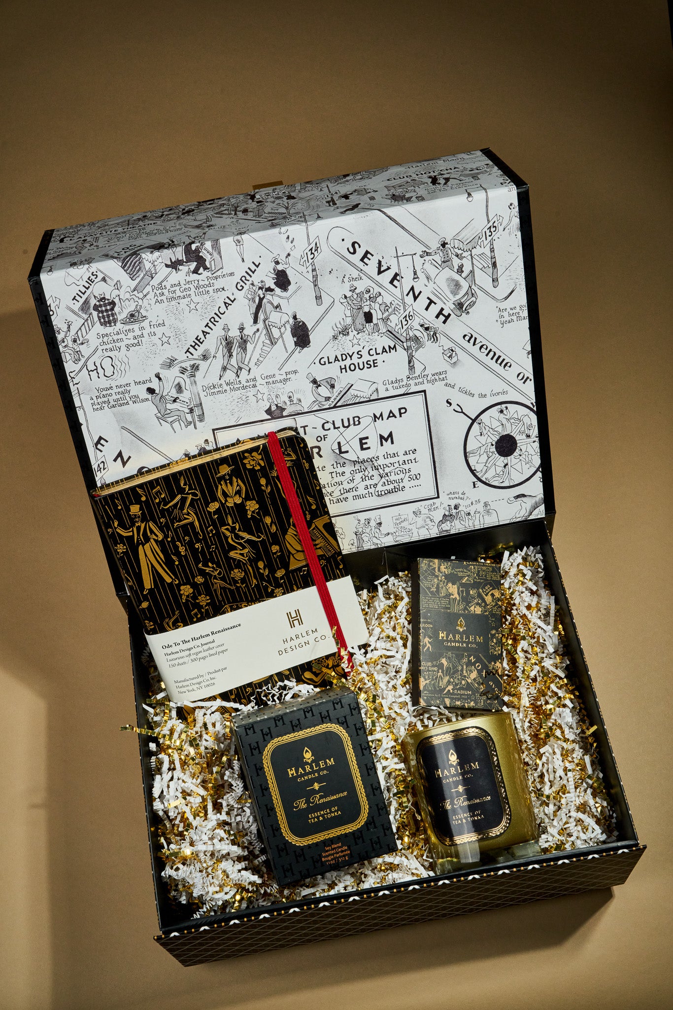 This is an image of our Renaissance stories gift box which include an 11 ounce Renaissance candle, our ode to the Harlem Renaissance, black and gold journal, and our black and gold nightclub map of Harlem, elegant matches.