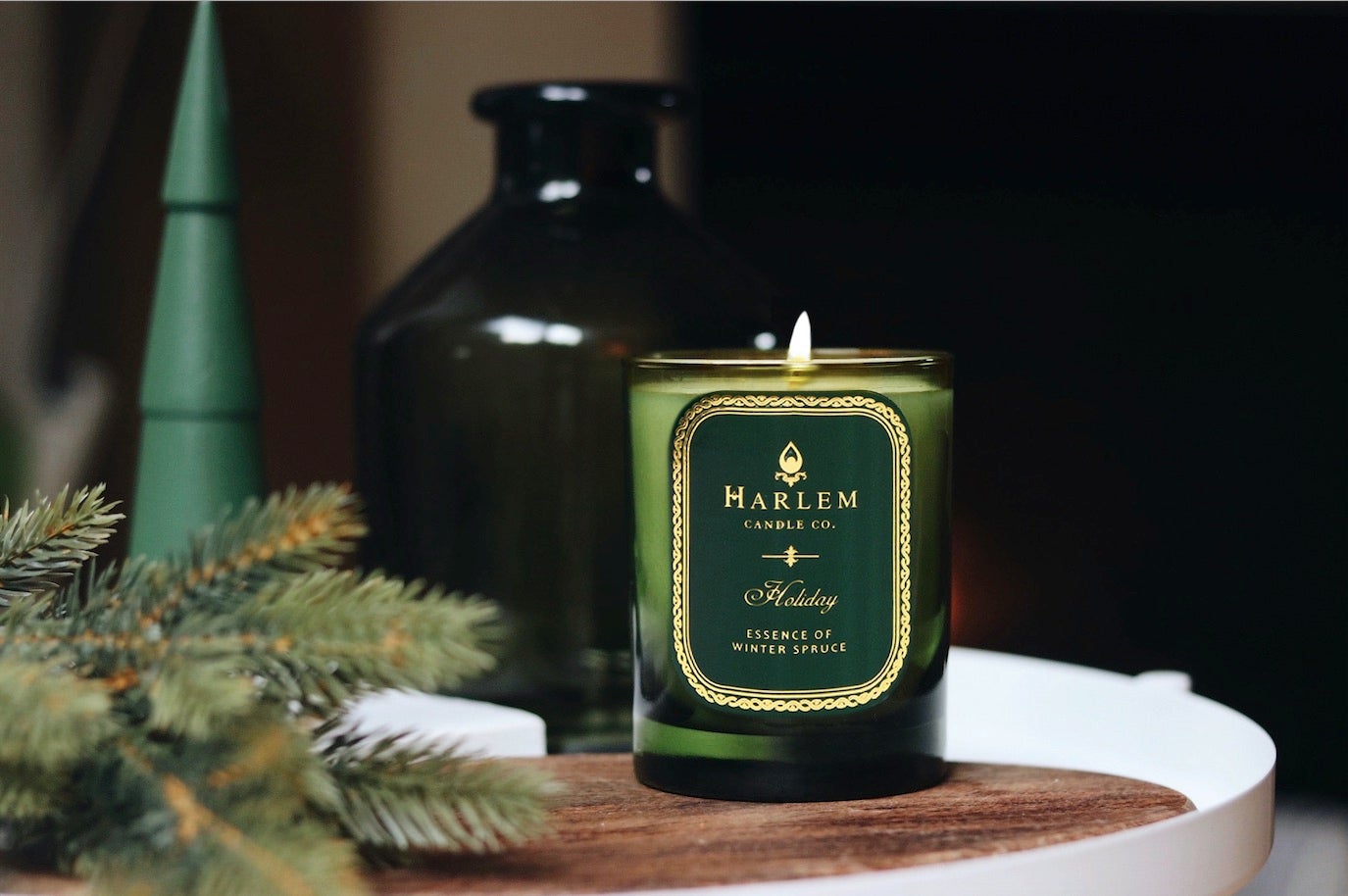 Hunter green glass 11 oz Holiday candle with one wick with a festive background